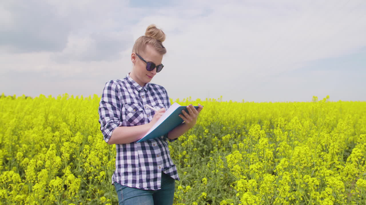Agricoltrice con gli occhiali prende appunti nel campo