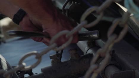 Working-man-tightening-bolt-with-wrench-on-farm-machinery,-Close-Up-on-Hands