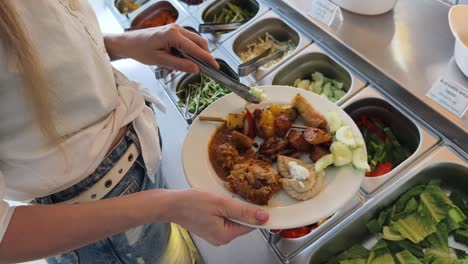 woman serving herself at a buffet with assorted dishes