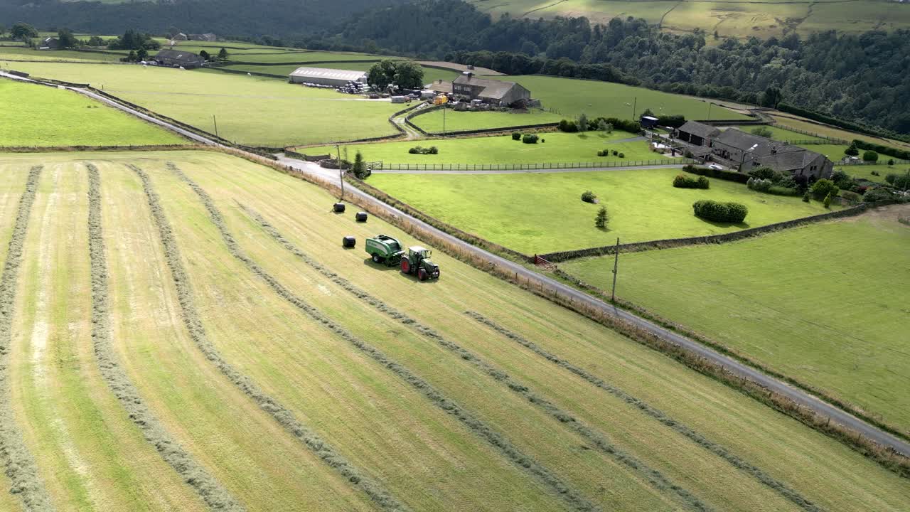 핼리팩스 웨스트 요크셔 영국의 시골 풍경에서 건초를 수확하는 녹색 트랙터