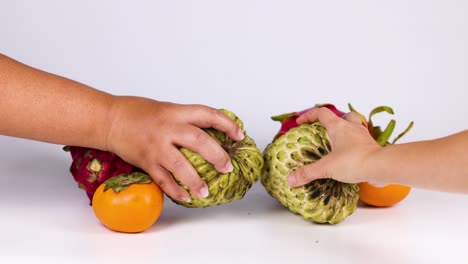 hands interact with fruits on a table