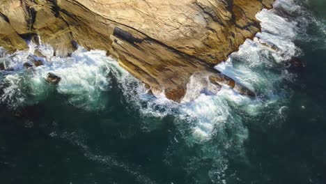 aerial static shot of sea waves breaking and eroding the rocky coastline