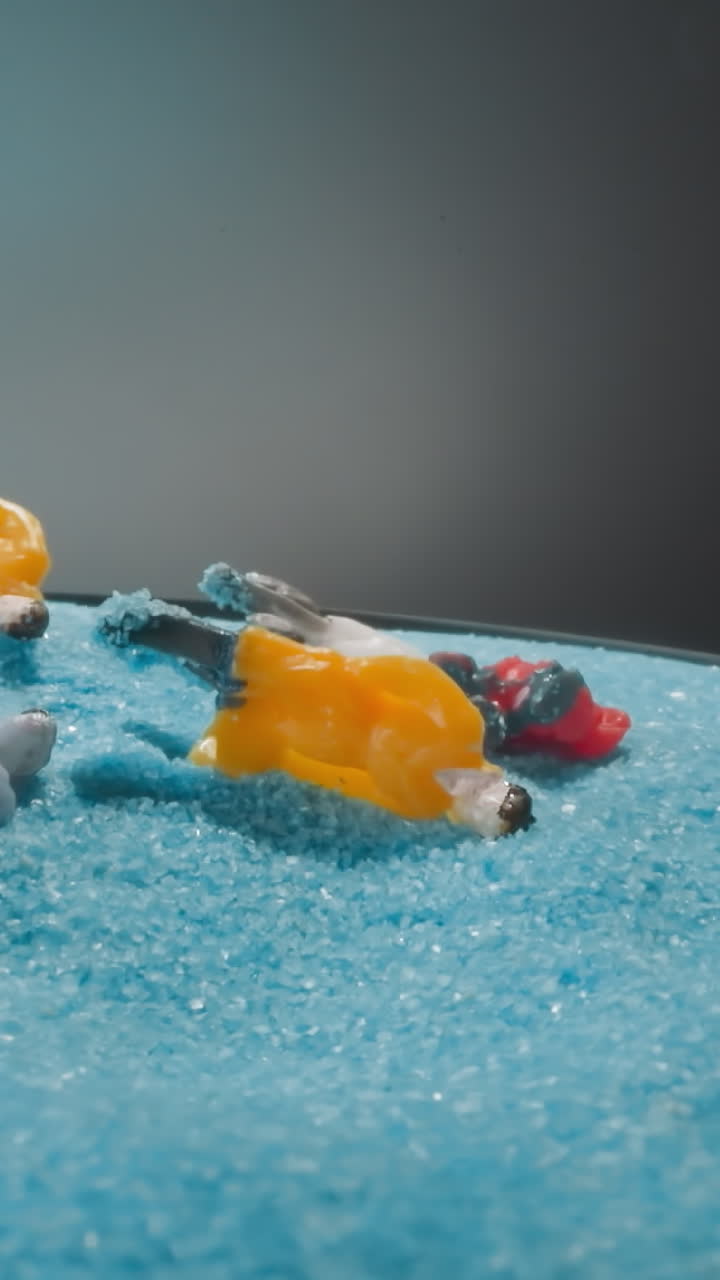 Artificial figurines with bags falling on soft blue sand after strong quake. Figures of people standing on bright sandy hill on grey background macro