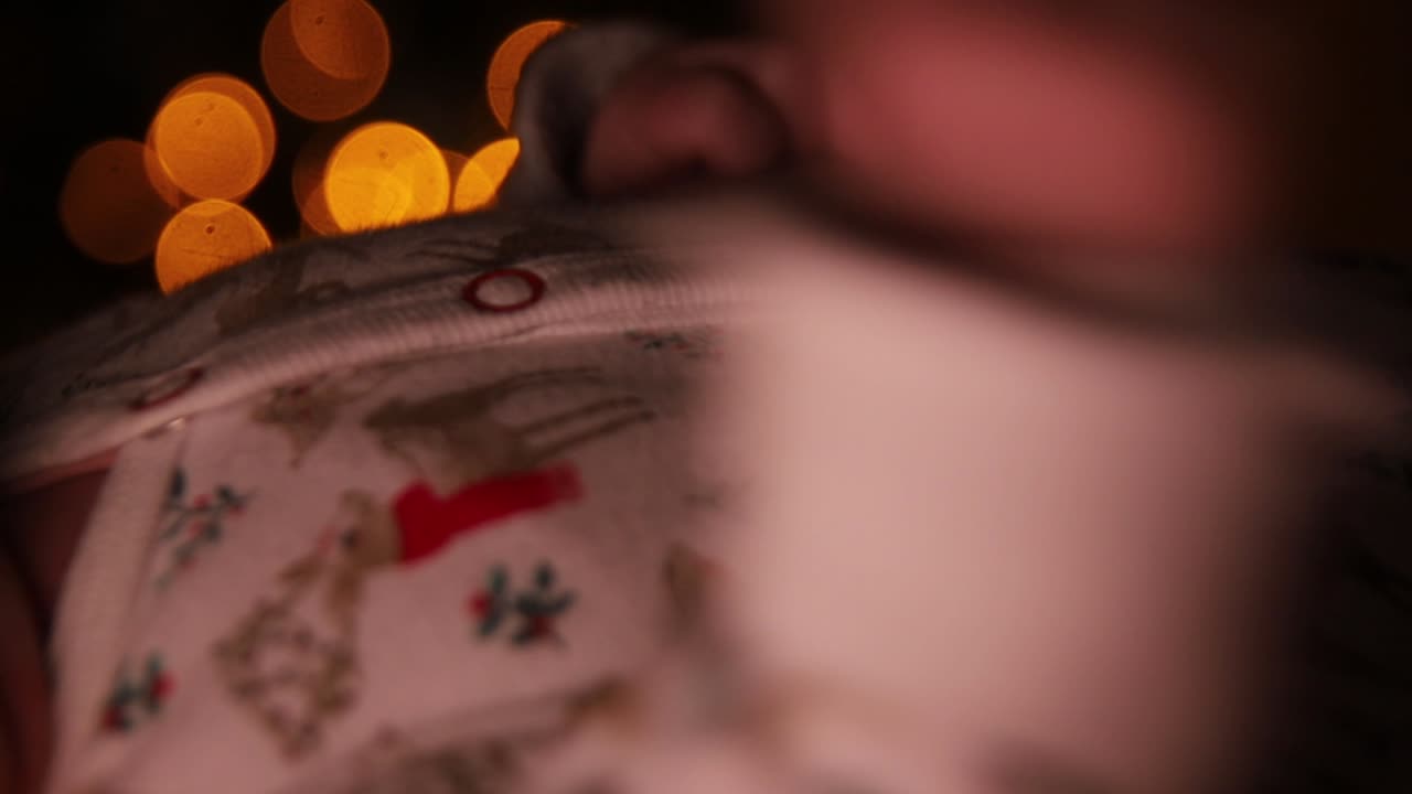 크리스마스 장식 트리 앞에서 그녀의 손을 움직이는 침대에 누워 웃는 아기 소녀