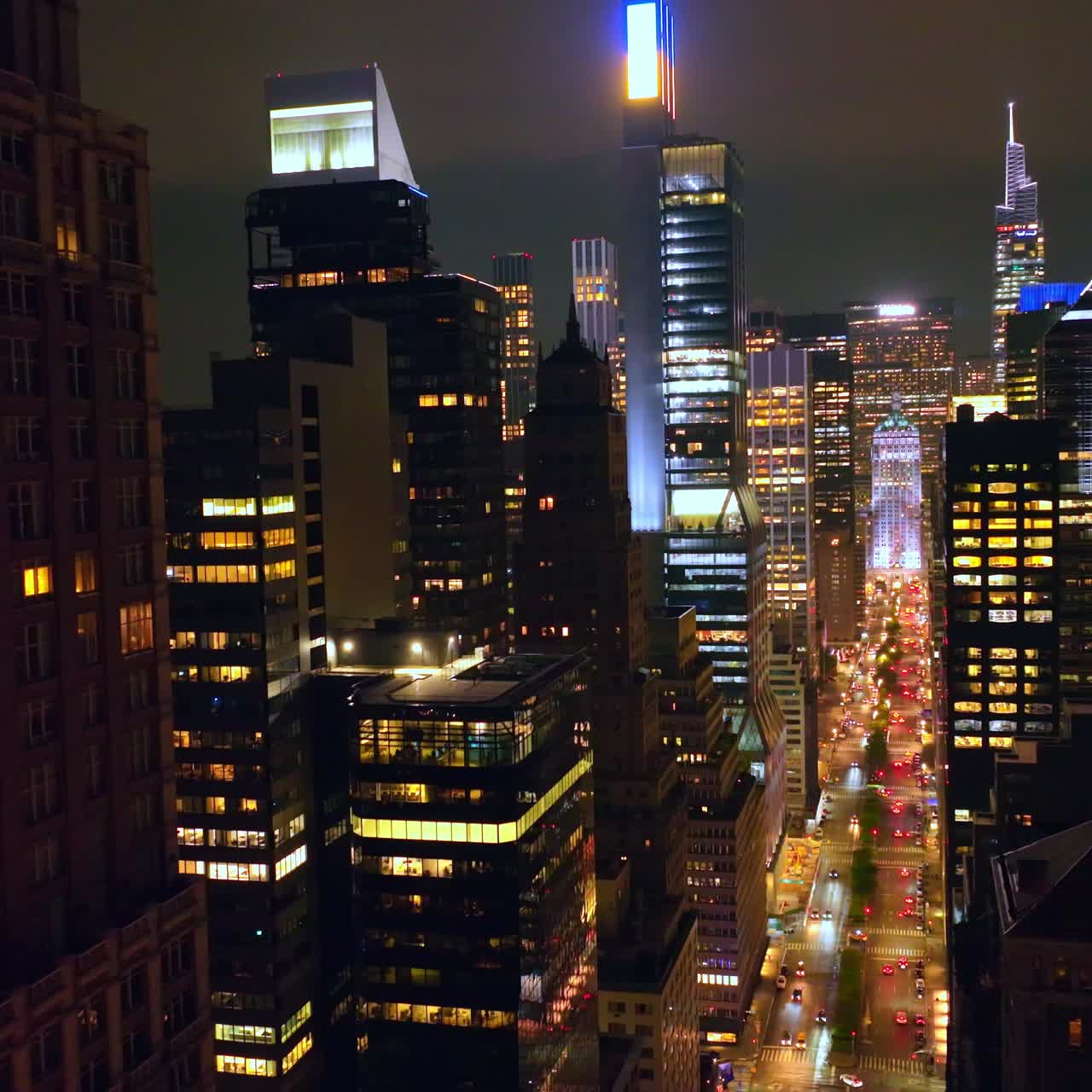 Amazing skyscrapers with lights on. Drone rising over glamorous buildings at night. Cloudy sky background