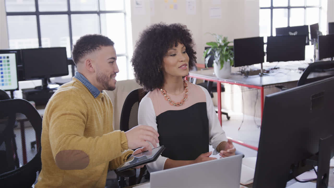 hombre y mujer felices y diversos colegas en el escritorio, usando tableta, computadora y hablando, en cámara lenta