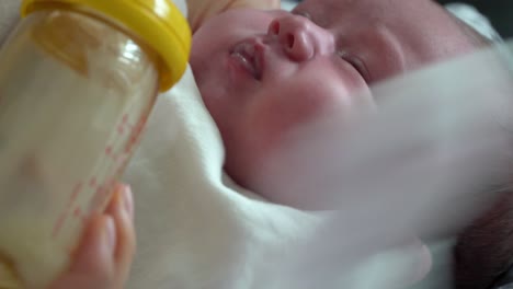 newborn baby refuses to drink milk but that drinking formula milk rapidly from the feeding bottle - extreme close up