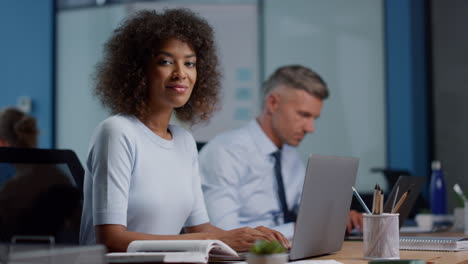 Mixed-race-businesswoman-using-laptop.-Female-executive-turning-head-to-camera