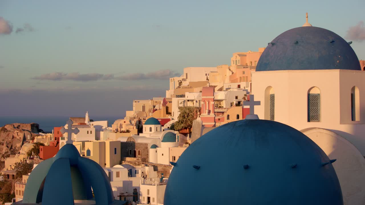 Breathtaking drone video capturing Santorini's stunning blue domes reflecting golden sunset light with vibrant Aegean sea backdrop, emphasizing serene ambiance and architectural beauty