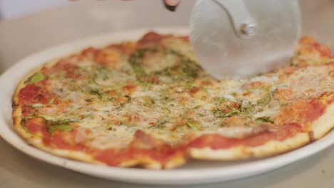 slow motion close-up of a person slicing pizza into multiple slices with a pizza cutter