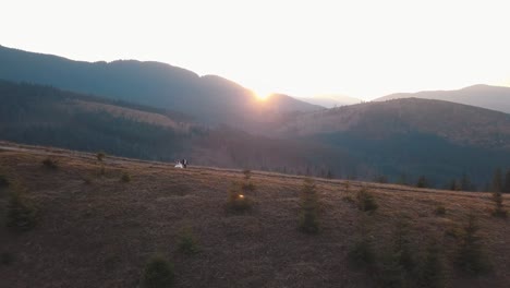 newlyweds running on a high slope of the mountain. groom and bride. aerial view