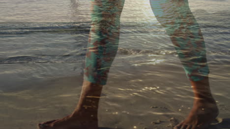 animation of legs of man walking on beach, over sun on sea