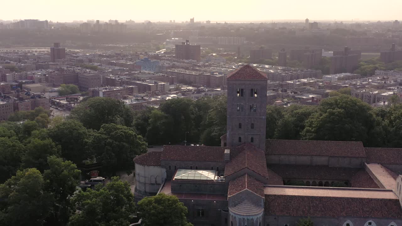 Luftoptagelse, der kredser med uret om The Cloisters i Upper Manhattan NYC i diset morgensommersolskin over mange kvarterer i den øvre del af byen.