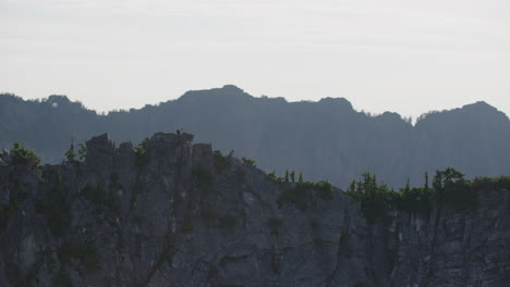 探险摄影师独自站在巨大的山脊上 景观景色,蒂姆·杜尔坎 极端宽度跟踪直升机 反时针轨道慢动作