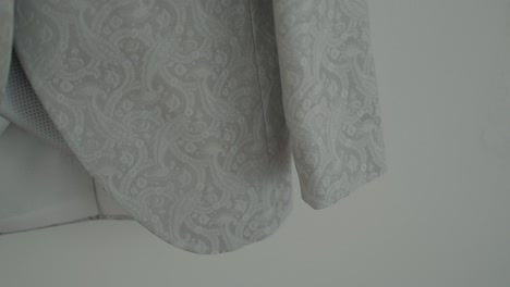 close-up of an intricately patterned wedding suit sleeve in light fabric, showcasing detailed embroidery