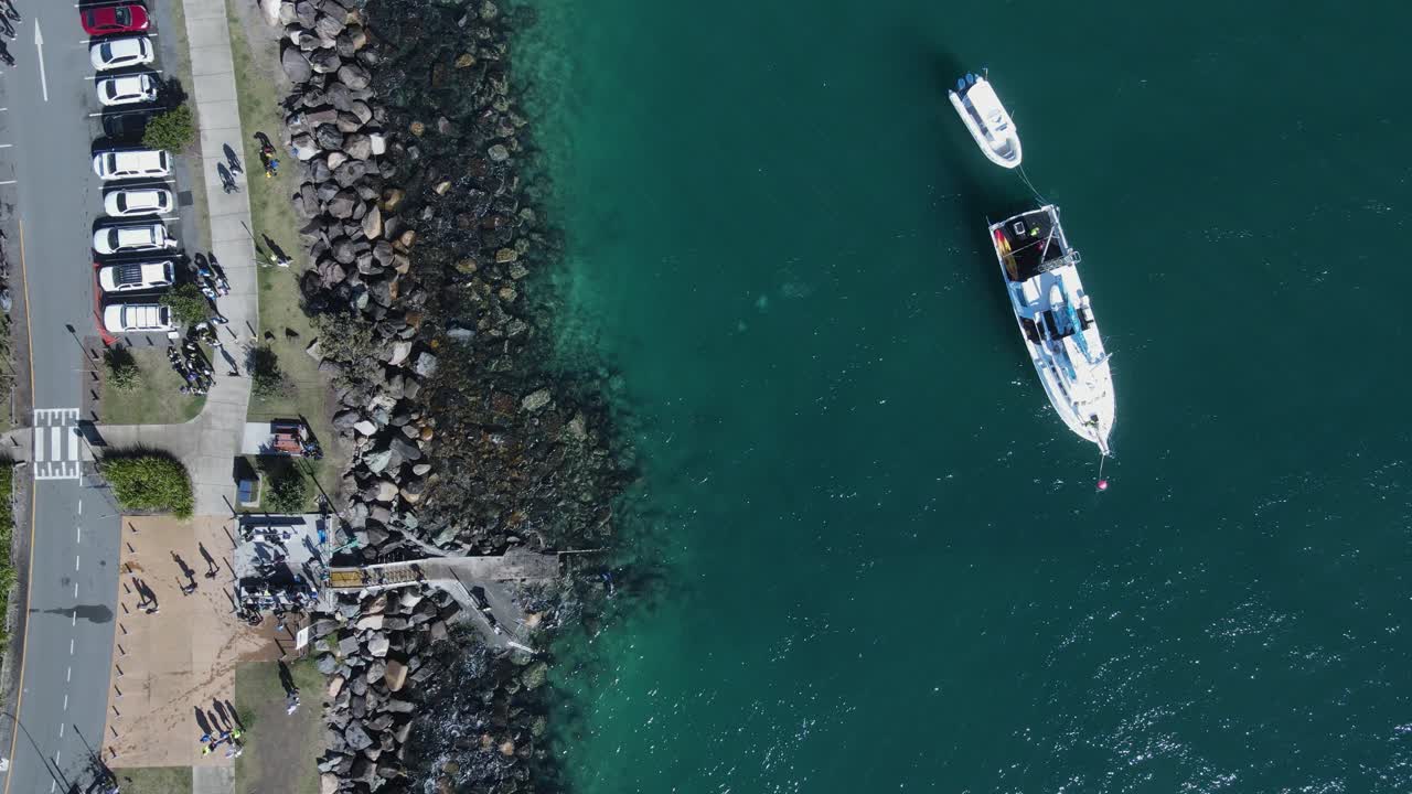 вид с высоты на аквалангистов под водой рядом с большим кораблем недалеко от скалистого берега