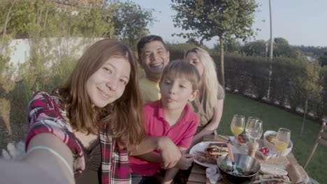 happy teenage girl taking selfie of parents and brother outdoors