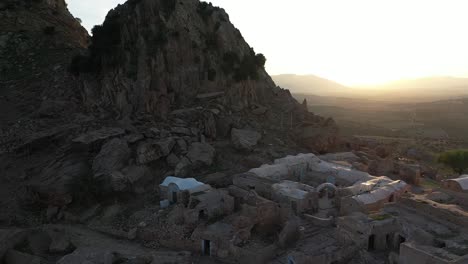 toma aérea volando hacia adelante sobre el antiguo pueblo que está sentado a la sombra del valle durante una hermosa y pacífica puesta de sol
