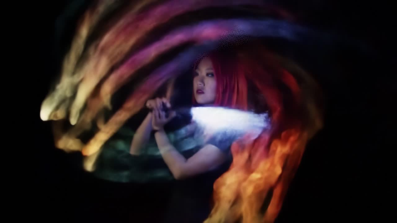 A Mesmerizing Display of Colorful Light Trails: An Enigmatic Performer Captivating the Audience with Whirling Motions in a Dark Setting