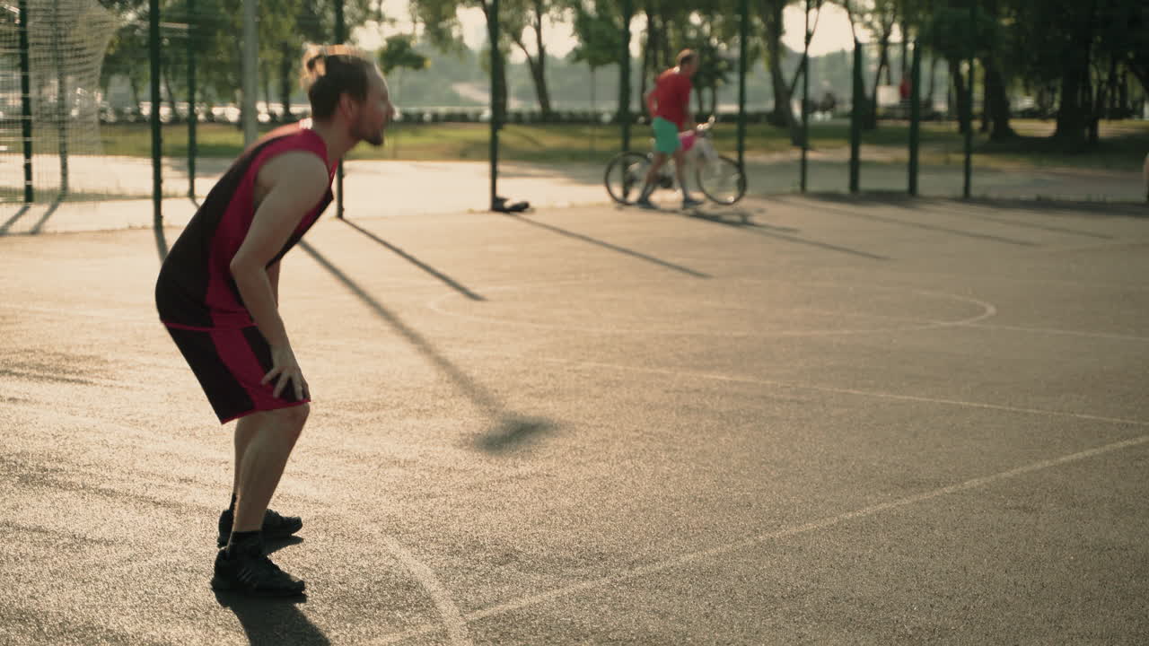 숙련된 남성 농구 선수가 상대 수비수를 상대로 공을 드리블하고 후프 1에 공을 던집니다.