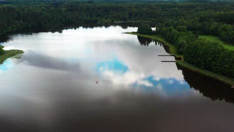 lago con reflejo del cielo y flotador de juguete inflable de agua, bosque verde alrededor