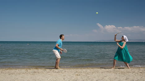 Paar-Spielt-Schläger-Und-Ball-Am-Strand