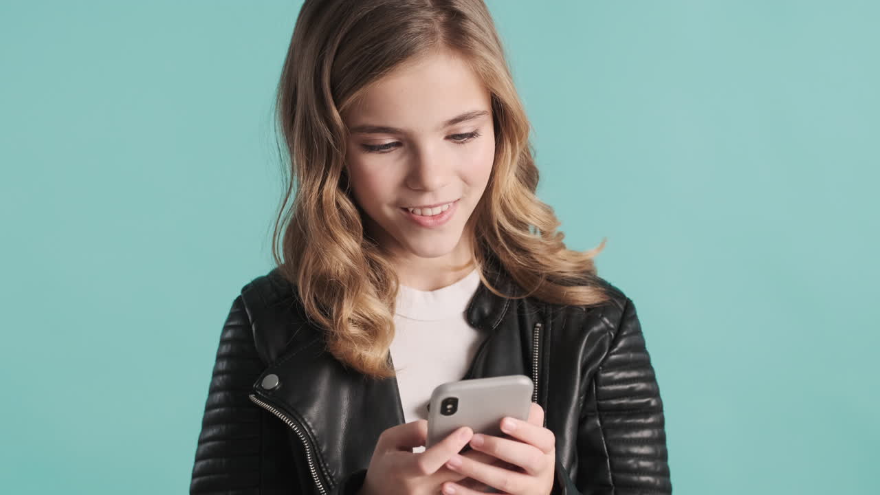 Teenage Caucasian girl in leather jacket using her smartphone.