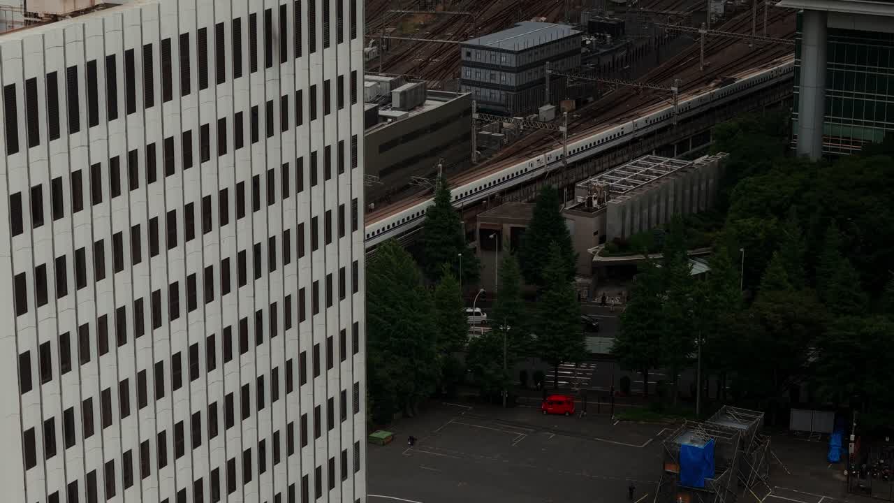 An urban scene with a high-speed train passing by a modern building