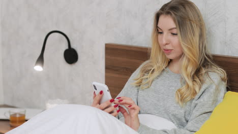 mujer usando teléfono inteligente en la cama