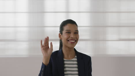 Retrato-De-Una-Joven-Mujer-De-Negocios-Independiente-De-Raza-Mixta-Riendo-Alegre-Agitando-La-Mano-Mirando-A-La-Cámara