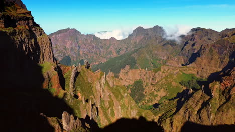 dangerous high rocks with little greenery growing on. cloudscape appears from behind the mountains. madeira islands, portugal. aerial view.