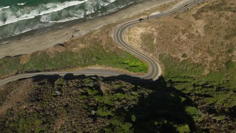 overhead aerial view of a sporty black car driving along winding the highway in california