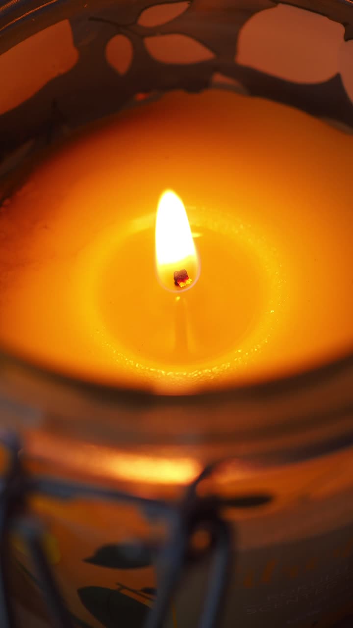Primo piano di una calda fiamma di candela che tremola in un barattolo.