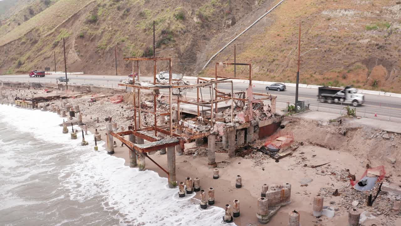 Aerial wide panning shot of a burned oceanfront home in the aftermath of the Palisades Fire in Malibu, California. 4K