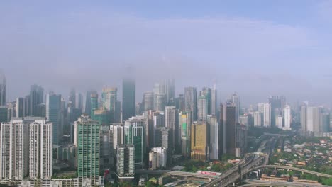 Aerial-rising-and-flying-towards-building-towers-of-KLCC-covered-by-clouds