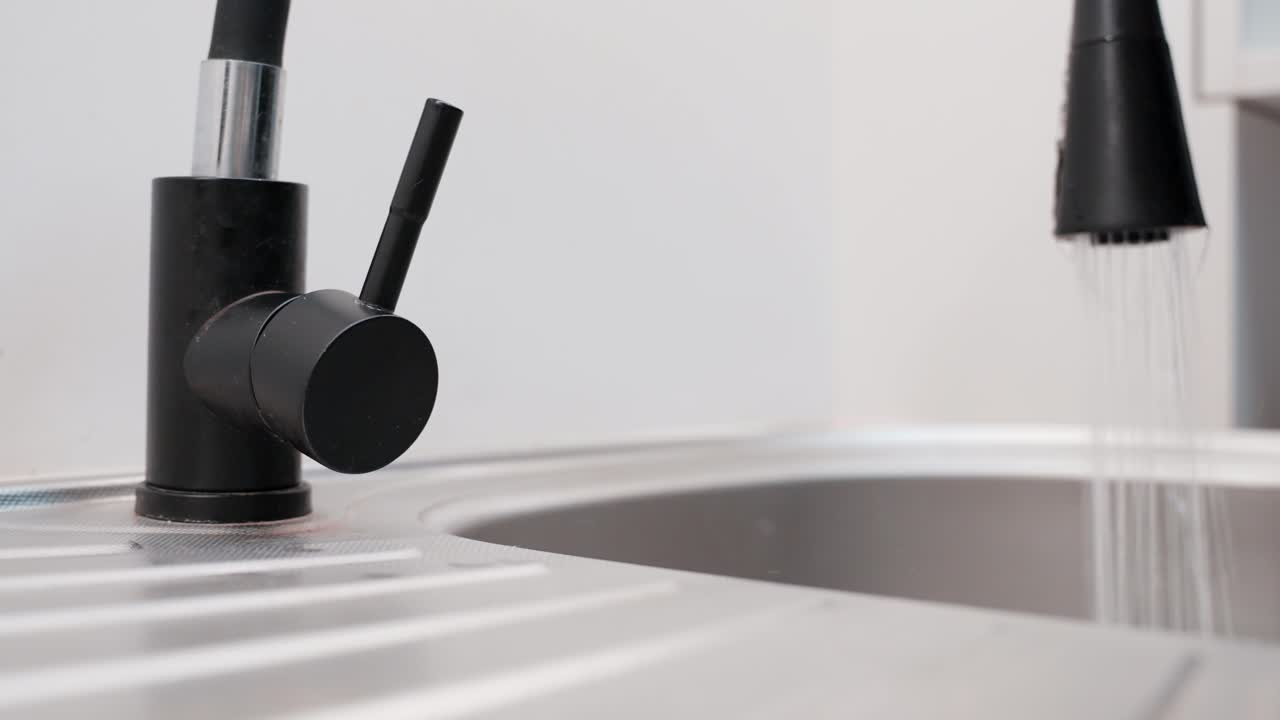 Close-up of a person opening the mobile faucet of a modern sink in slow motion