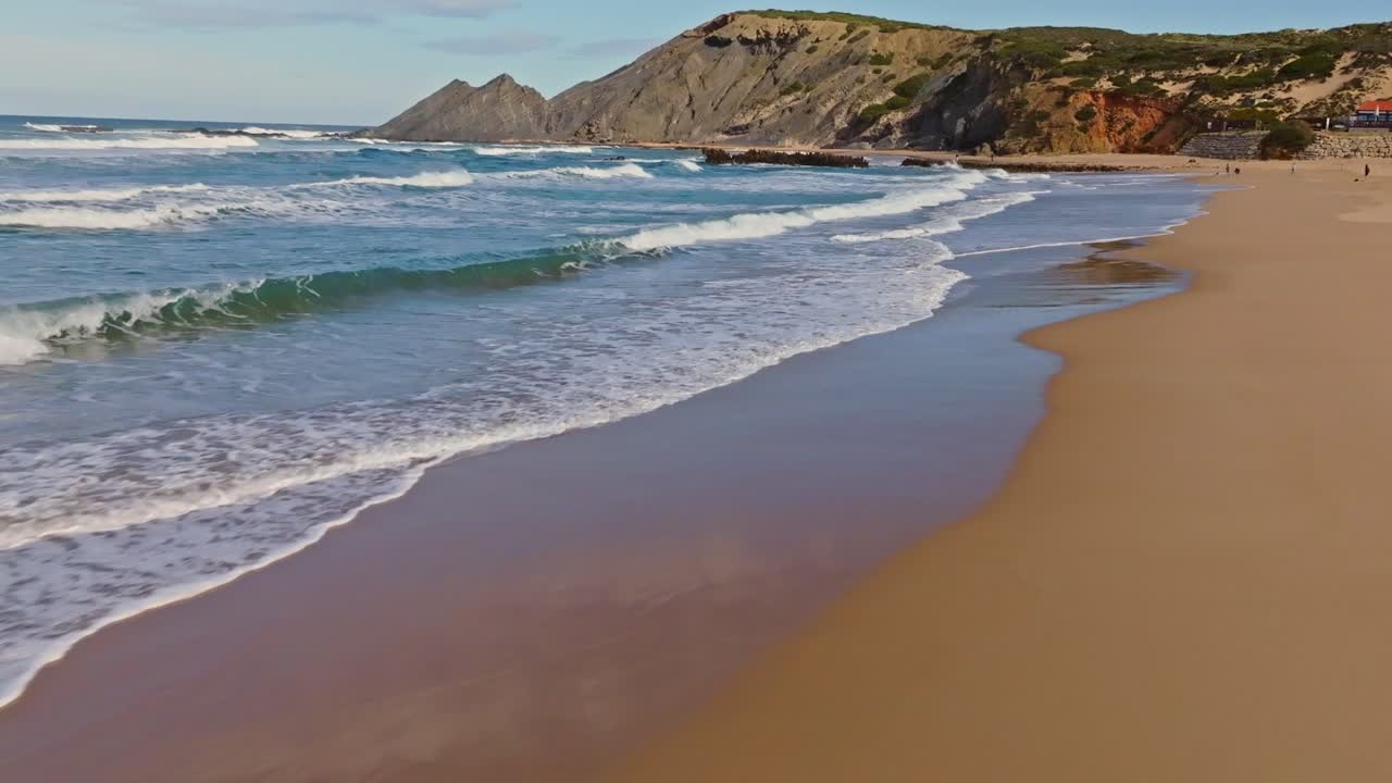 Drone flying low from the beach and soaring over the waves