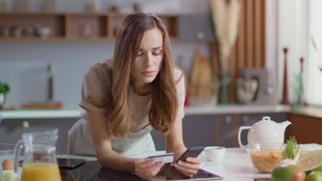 woman taking on smartphone at kitchen. lady drinking coffee in morning at home