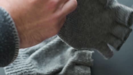 detalle de manos poniéndose viejos guantes grises de invierno sin dedos