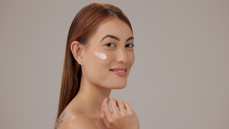 mujer sonriente aplicando crema facial