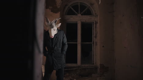 man in goat mask in abandoned building