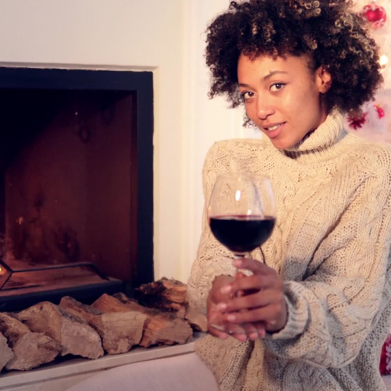 Pretty woman holds wine glass beside fireplace