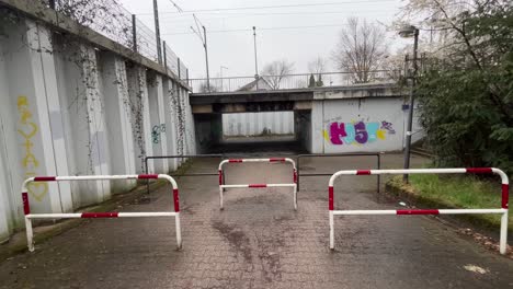 dark-old-railway-underpass-for-pedestrians-shielded-with-red-and-white-sidewalk-fence