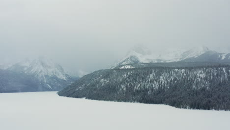 Aerial-footage-of-foggy-Sawtooth-Mountains-looming-over-frozen-Redfish-Lake