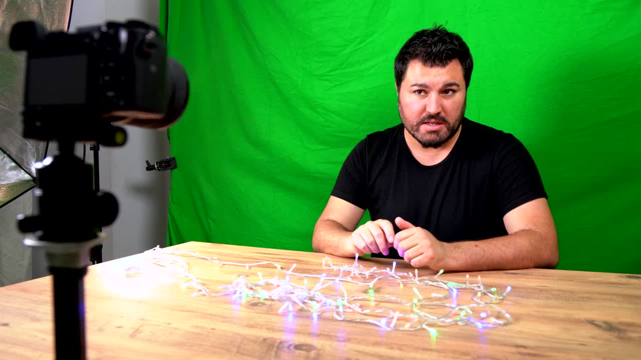 Uomo vlogger che registra un video per YouTube nel suo studio domestico con schermo verde e telecamera