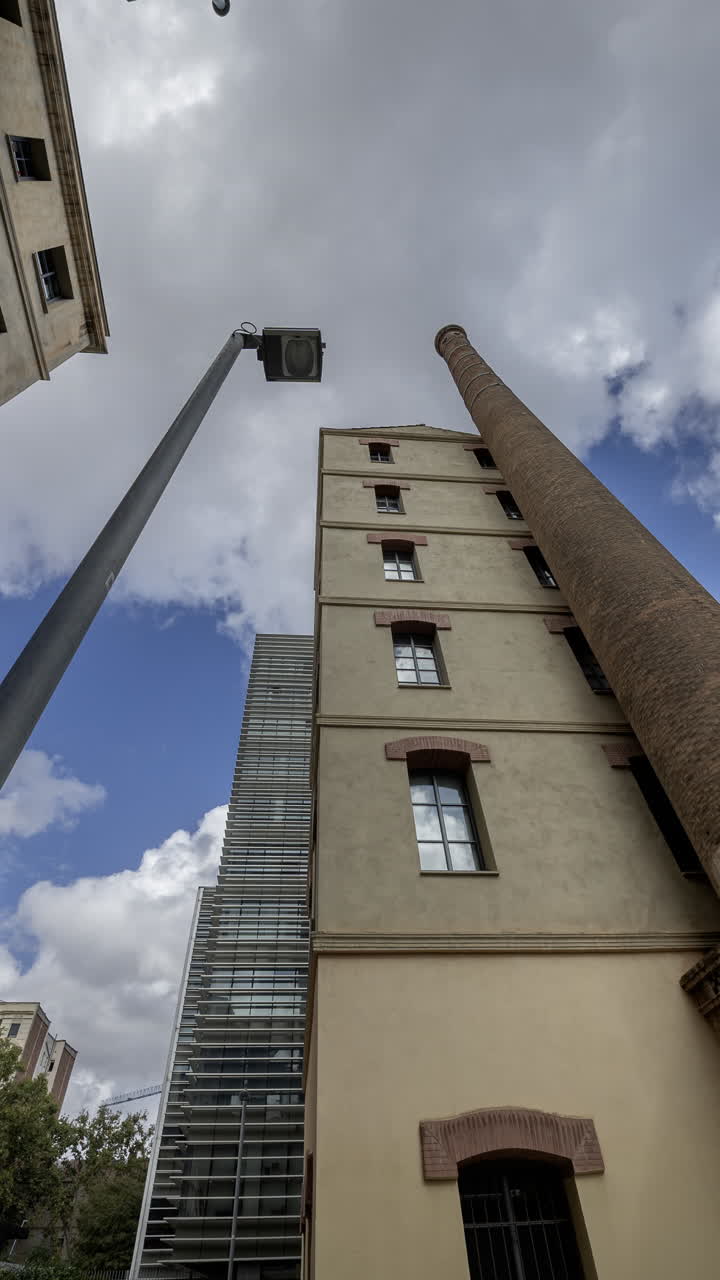 Old factory chimney and apartment buildings in barcelona in vertical