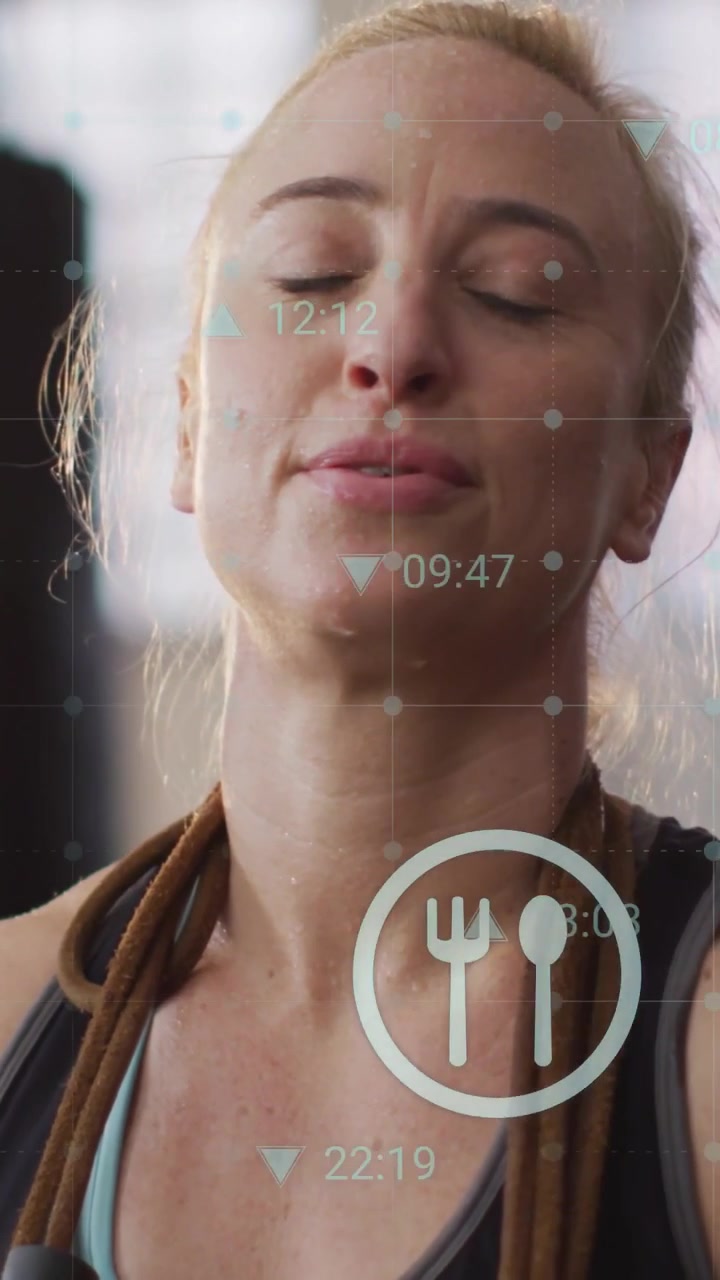 Vídeo vertical: Mulher segurando corda de pular após o exercício, câmera subindo enquanto temporizadores HUD monitoram o condicionamento físico.