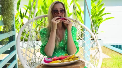 woman eating dragon fruit in a hanging chair