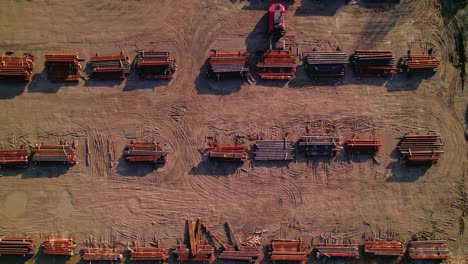 top down forkift driver unloading steel bar on yard full of staked metal bars