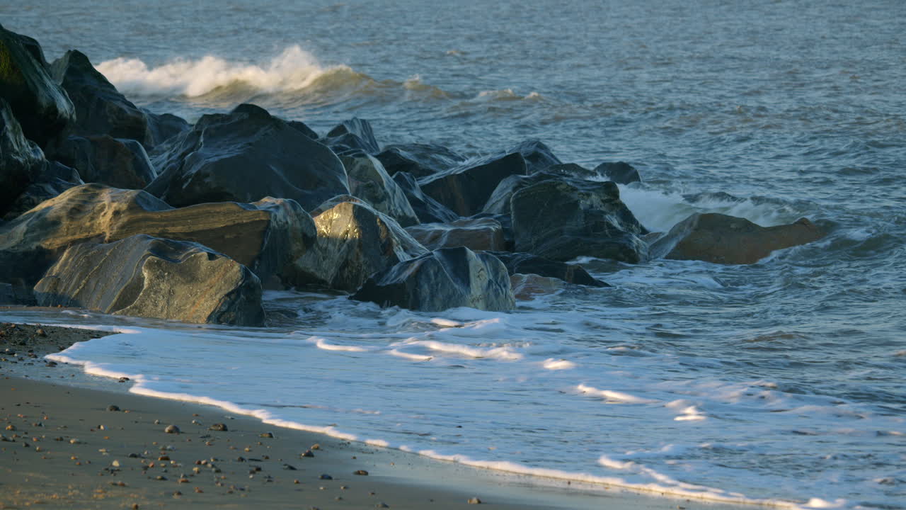 Mid Shot of the sea gently crashing over sea defence rocks on the beach at Caister on Sea